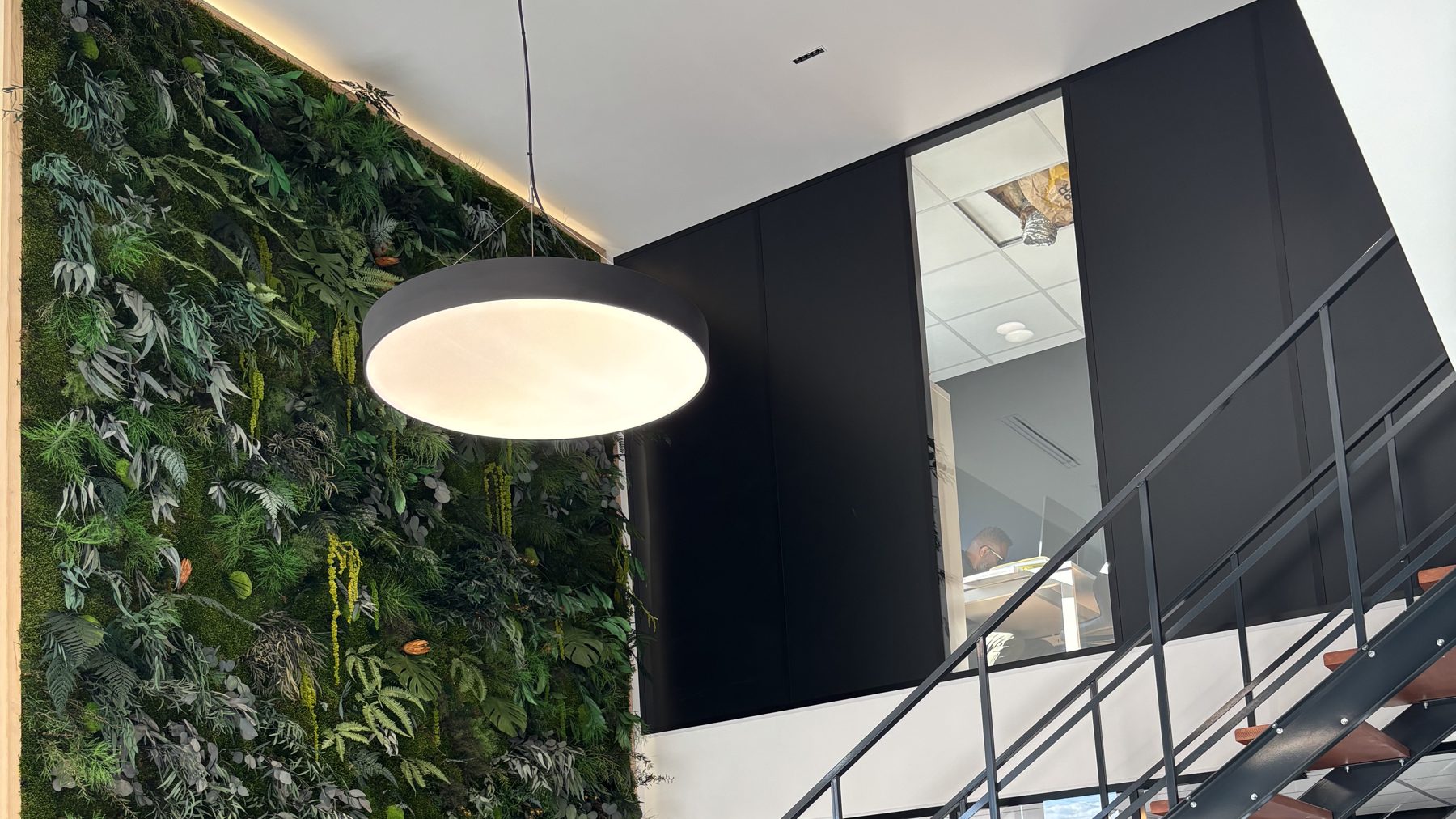 Mur végétal stabilisé de grande hauteur dans un hall à double hauteur, sol béton et escalier métallique — traitement acoustique par Garden Events (Hydraulia)