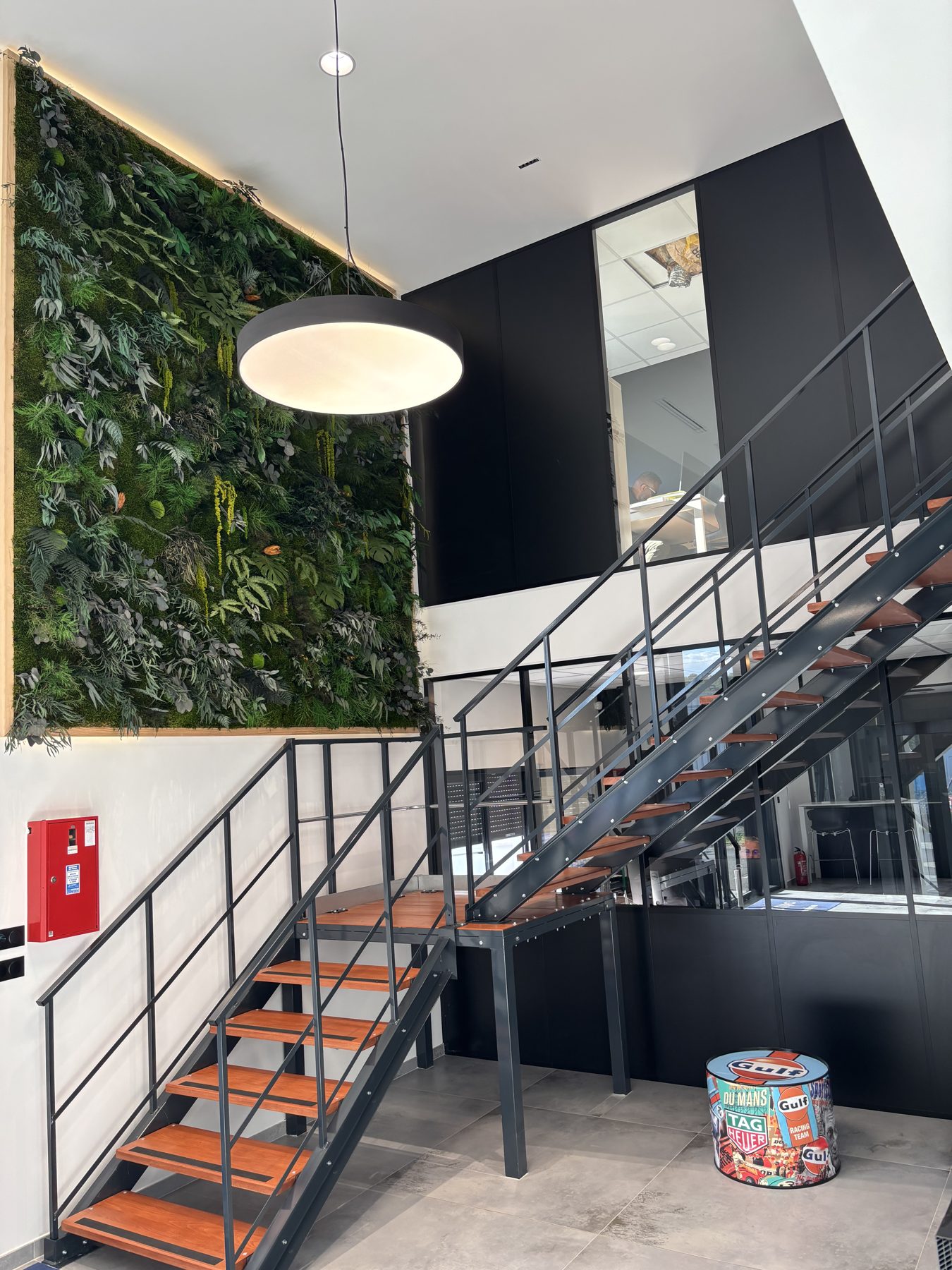 Mur végétal stabilisé de grande hauteur dans un hall d'entreprise à double hauteur, escalier métallique et sol béton — traitement acoustique par Garden Events (Hydraulia)